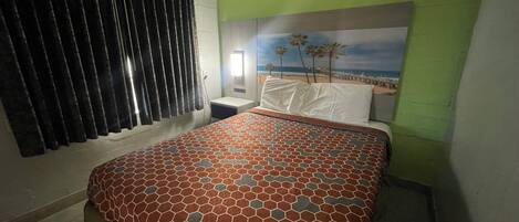 A bedroom with a bed, a nightstand, a window with curtains, and a wall mural.