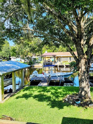 A marina with boats docked, a covered boat house, and a building in the background.