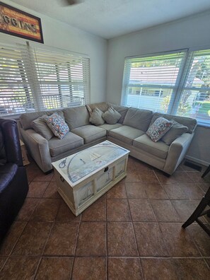 Relax in this inviting living room with a comfortable sofa, decorative chest, and large windows.