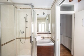 A bathroom with a glass-enclosed shower, a sink, and a mirror above it.