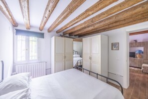 A bedroom with a bed, wooden beams, a window, and a wardrobe.