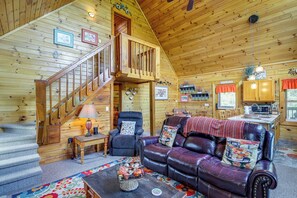 Cozy cabin-style accommodation with a wooden staircase, leather sofa, and dining area featuring a microwave and coffee maker.