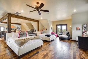 Ampia camera da letto con un letto grande, due letti più piccoli, una ventola a soffitto e vista su un balcone.
