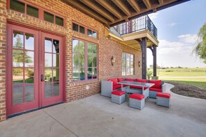 Una veranda coperta con mobili da esterno, un edificio in mattoni e un balcone.