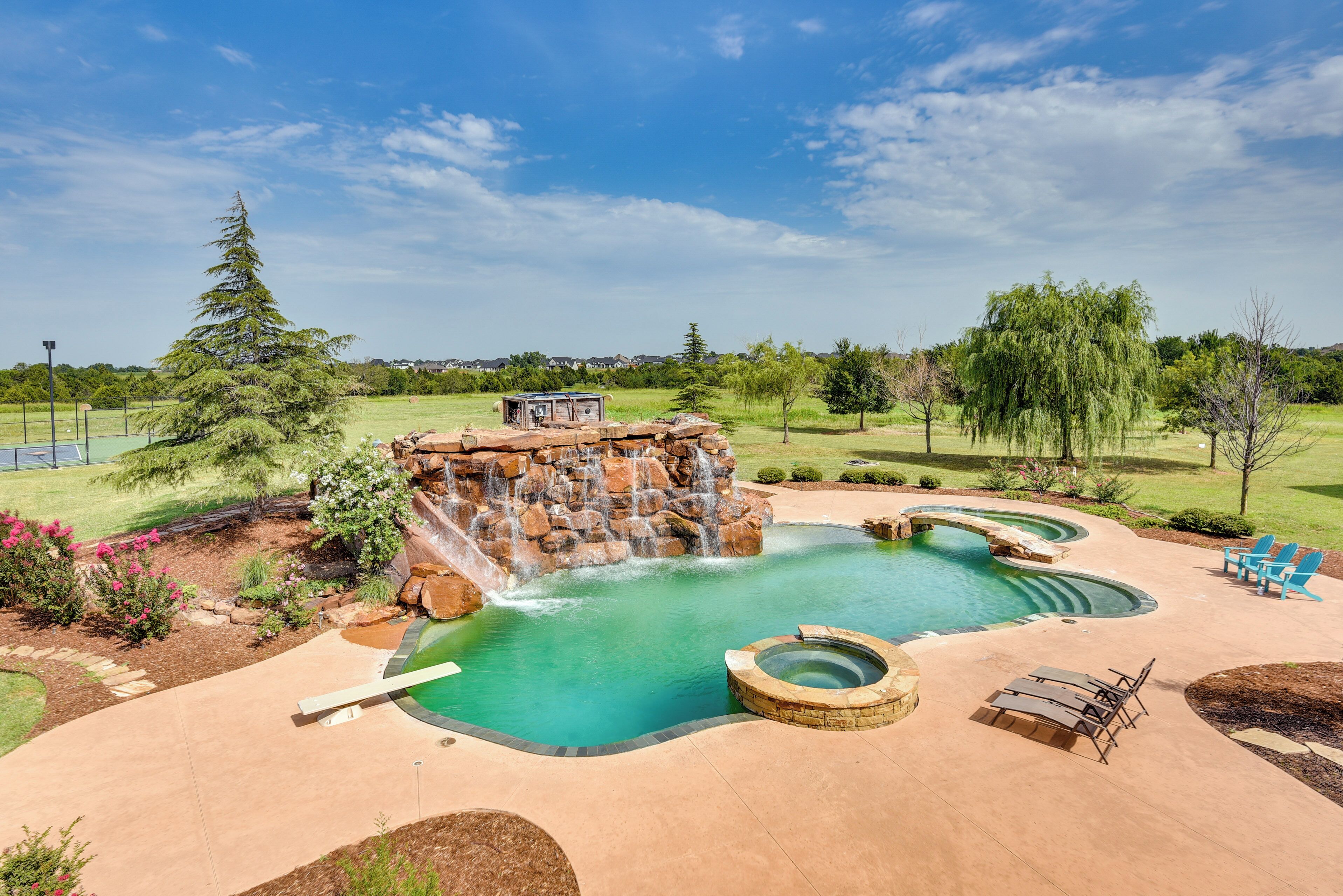 Un patio trasero con piscina, jacuzzi y una cascada.
