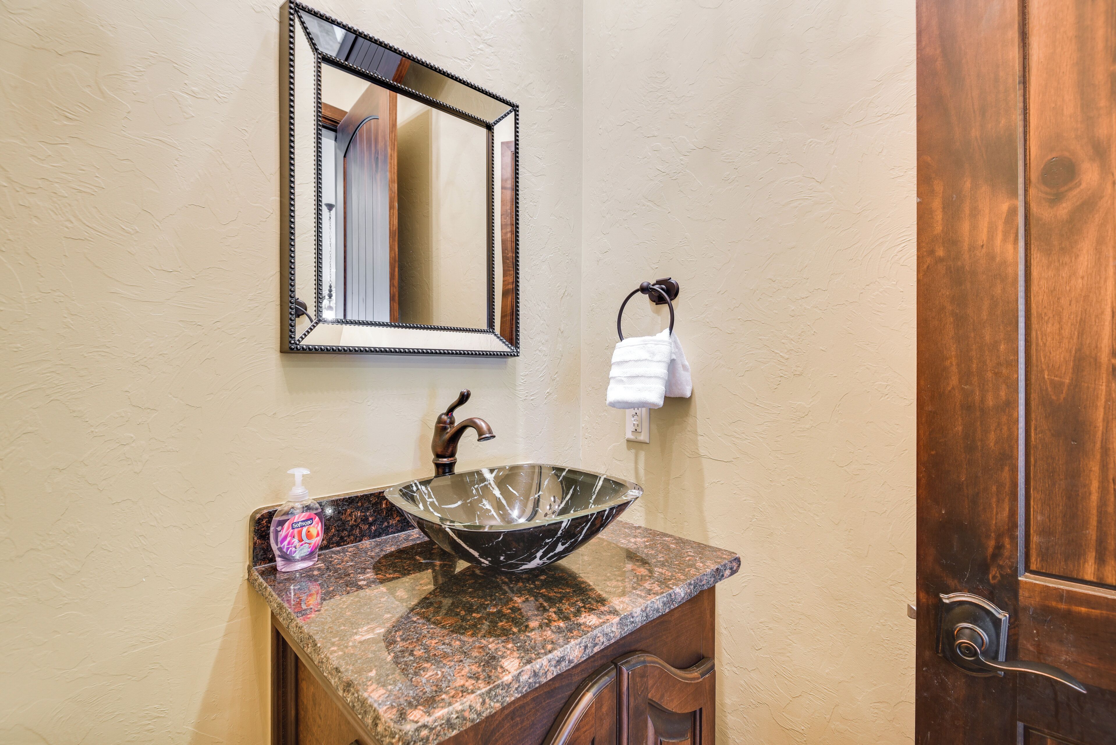 A bathroom with a marble sink, a mirror, and a wooden door.