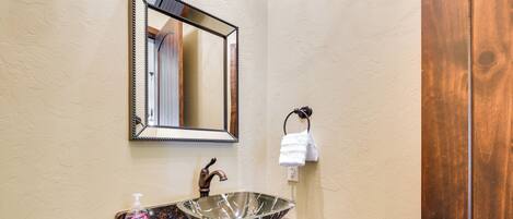 A bathroom with a marble sink, a mirror, and a wooden door.