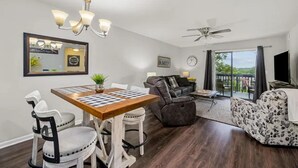 A spacious living room with a dining table, a sofa, and a ceiling fan. - Fairway Bunker Hideaway - Serene Retreat! (Branson)