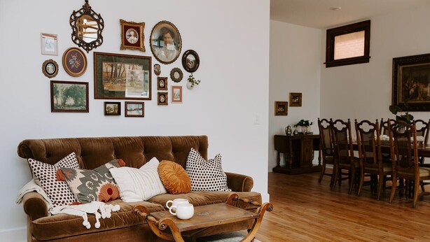Un salon avec un canapé marron, une table basse en bois et un coin repas comprenant des chaises et une table en bois.