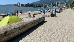 A beach with tents, a log, and people. - WestCoast Garden Suite | 1 Bedroom | Private | Quiet | Central | Modern (North Vancouver)