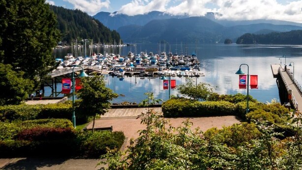 A marina with boats docked, surrounded by greenery and mountains in the background. - WestCoast Garden Suite | 1 Bedroom | Private | Quiet | Central | Modern (North Vancouver)