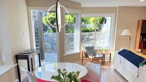 A modern living room with a round dining table, a sofa, and a chair. There is a potted plant on the table. - WestCoast Garden Suite | 1 Bedroom | Private | Quiet | Central | Modern (North Vancouver)