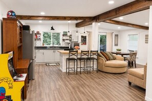 A modern kitchen with a central island, wooden beams, and a dining area with a sofa and chairs.