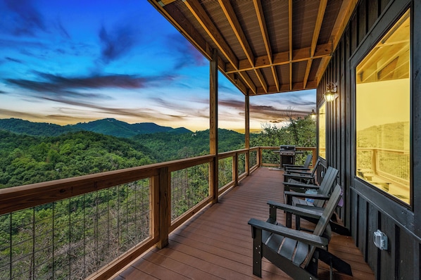 Um deck de madeira com guarda-corpo, com vista para uma paisagem verde exuberante.