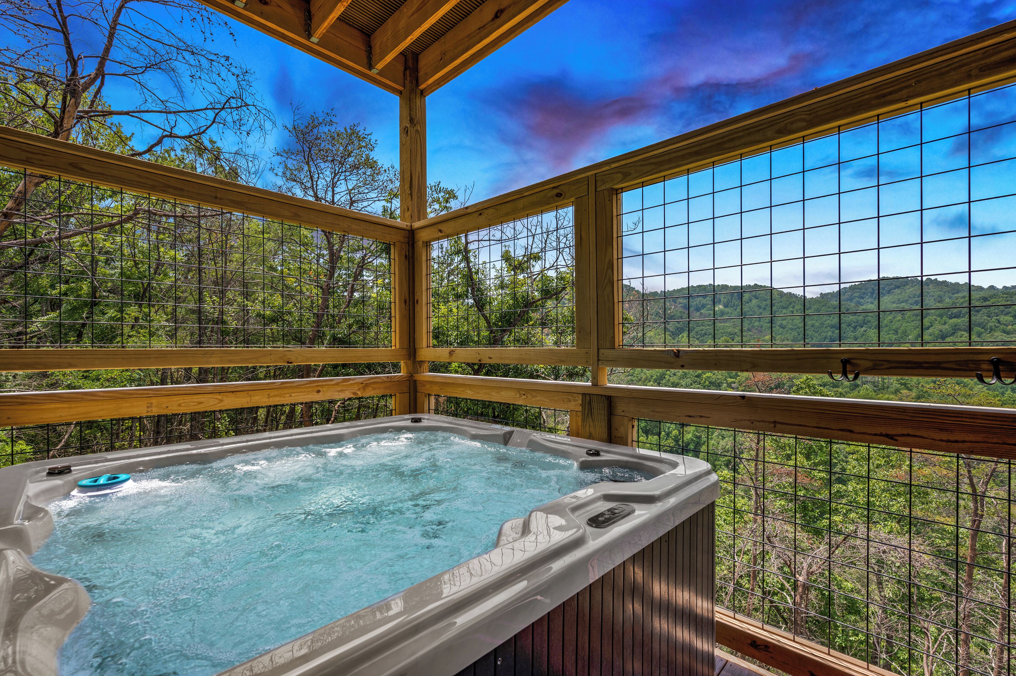 A hot tub with a view of a forest and mountains.
