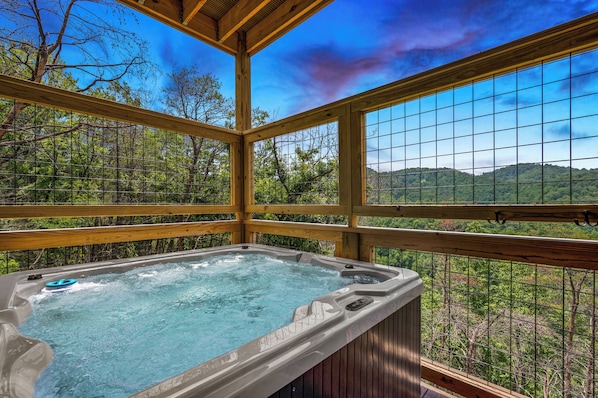 Uma banheira de hidromassagem com vista para uma floresta e montanhas.