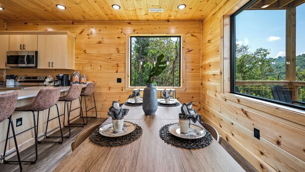 Une cuisine moderne avec des murs en bois, une grande fenêtre et un coin bar avec des tabourets.