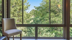 A room with a large window offering a view of a forested area. - Golf View Peek-a-boo (Branson)