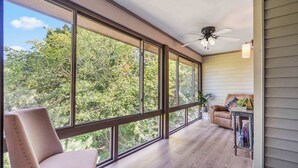 A spacious room with large windows, a ceiling fan, and a cozy seating area with a chair and a sofa. - Golf View Peek-a-boo (Branson)