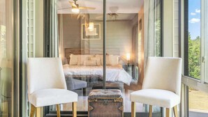 A bedroom with a large bed, two chairs, a chest of drawers, and a ceiling fan. - Golf View Peek-a-boo (Branson)