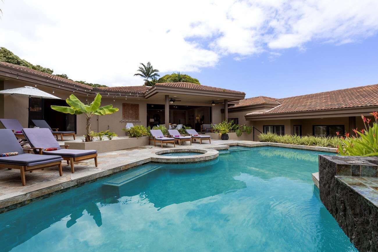 Una piscina con lettini e una zona patio coperta.