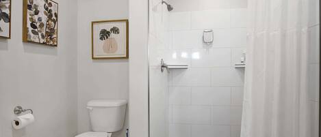 A modern bathroom with a toilet, shower, and toilet paper dispenser.