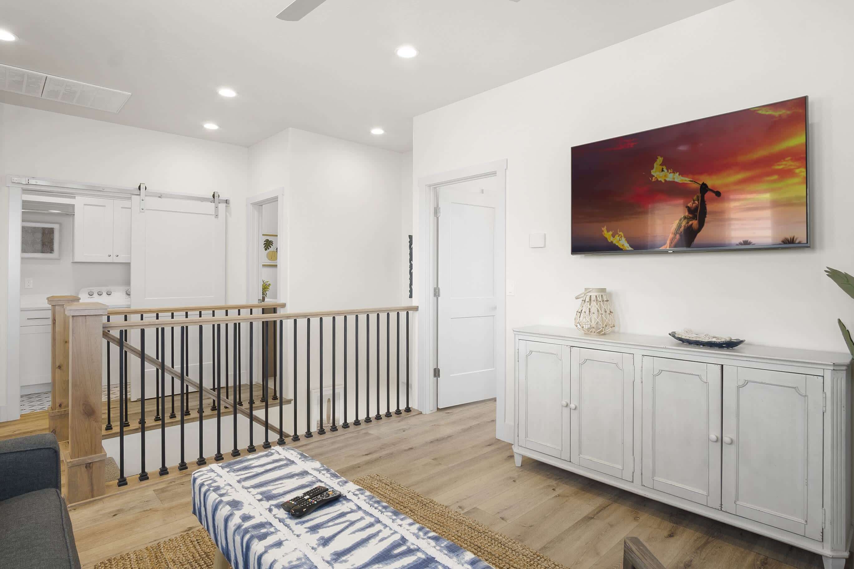 A modern living room with a staircase, a dining area, and a kitchen.