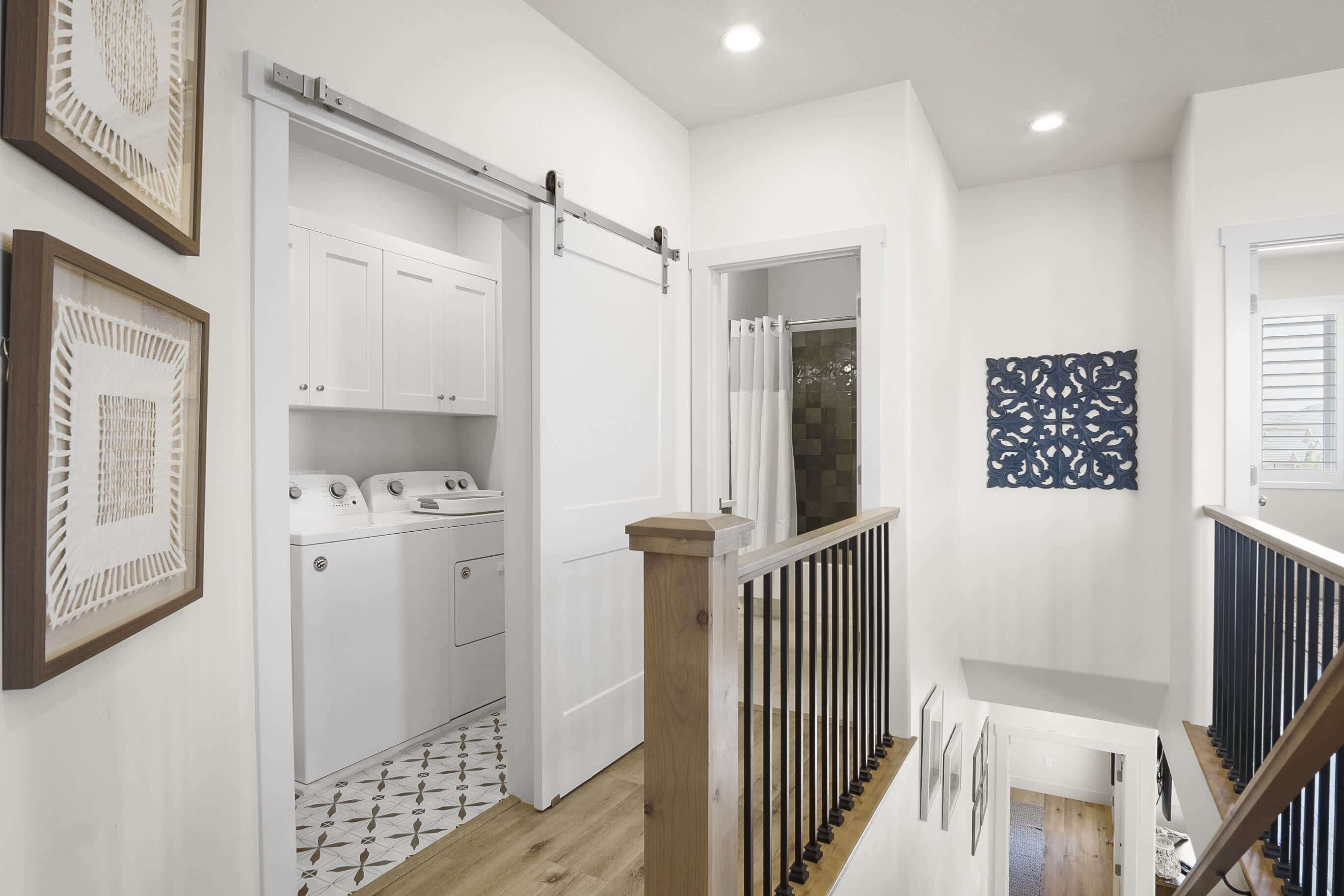 A laundry area with a white washing machine and dryer, a sliding door, and a patterned floor.