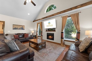 A living room with a fireplace, leather sofas, a coffee table, and a television. - Hickory Hideaway - Communal Pool Access (Hollister)