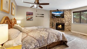 A bedroom with a bed, a ceiling fan, a fireplace, framed pictures, and a window. - Heavenly Haven - Hot Tub + Seasonal HOA Pool (Zephyr Cove)
