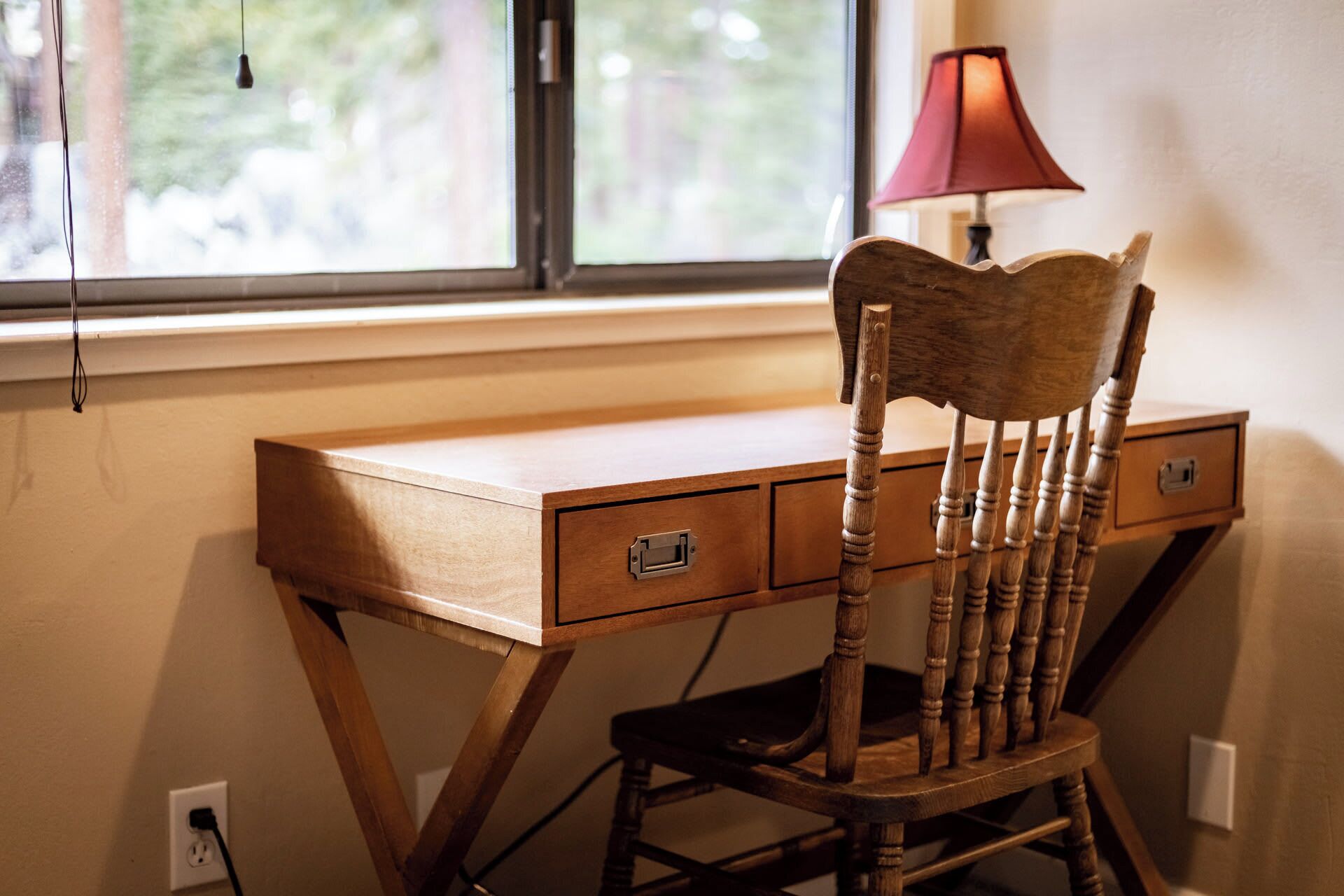 A wooden desk with drawers and a chair with a curved backrest.