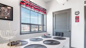 Quarto moderno com uma janela grande, uma porta com placa e uma mesa com jogos americanos.