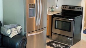 Eine kompakte Küche mit Edelstahlgeräten, darunter ein Kühlschrank, eine Mikrowelle und ein Backofen.