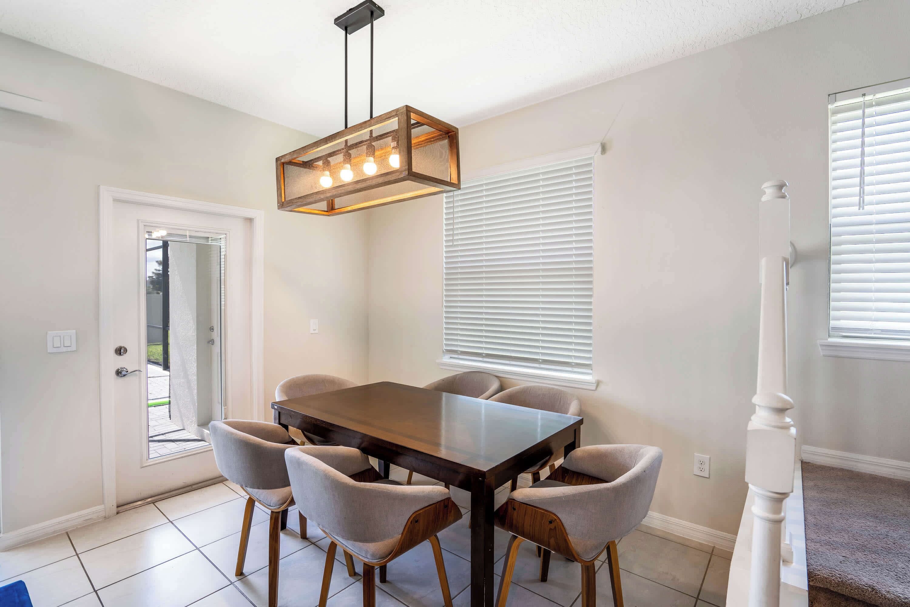 A dining area with a rectangular table, six chairs, and a hanging light fixture.