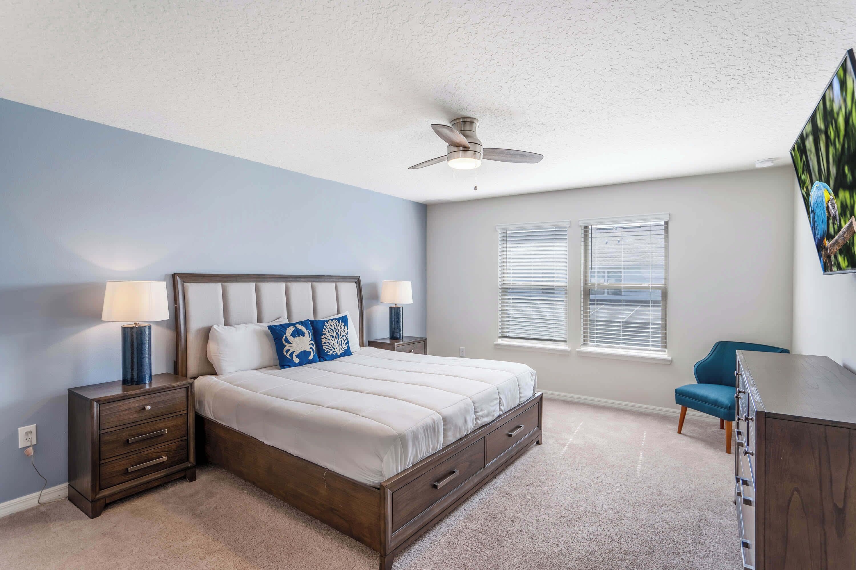 A bedroom with a bed, nightstands, a desk, and a ceiling fan.