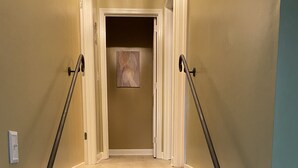 Eine Treppe mit Holzdielen und schwarzen Geländern, die zu einem Raum mit einem gerahmten Bild an der Wand führt.