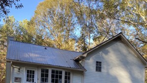 Ein Haus mit Veranda, Sitzbereich im Freien und einem kleinen Garten.