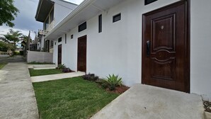Un edificio moderno con fachada blanca, varias puertas y un césped bien cuidado.