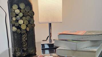 A glass table with a decorative bottle, a lamp, and a stack of books.
