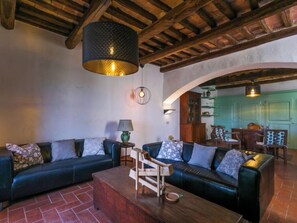 A cozy living room with a dark green sofa set, a wooden coffee table, and a hanging light fixture.