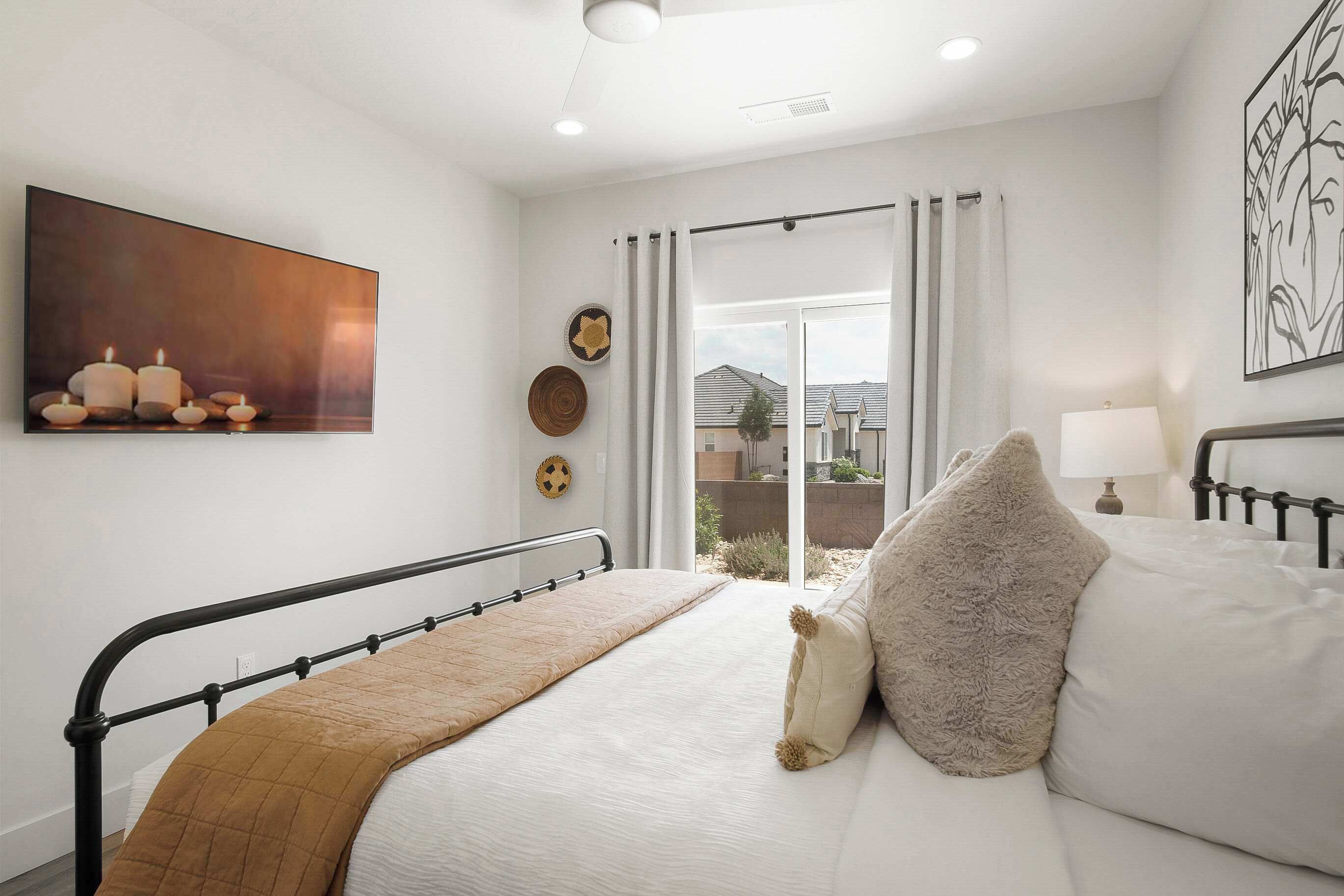 Een slaapkamer met een bed, een raam met gordijnen, een schilderij aan de muur en uitzicht op buiten.