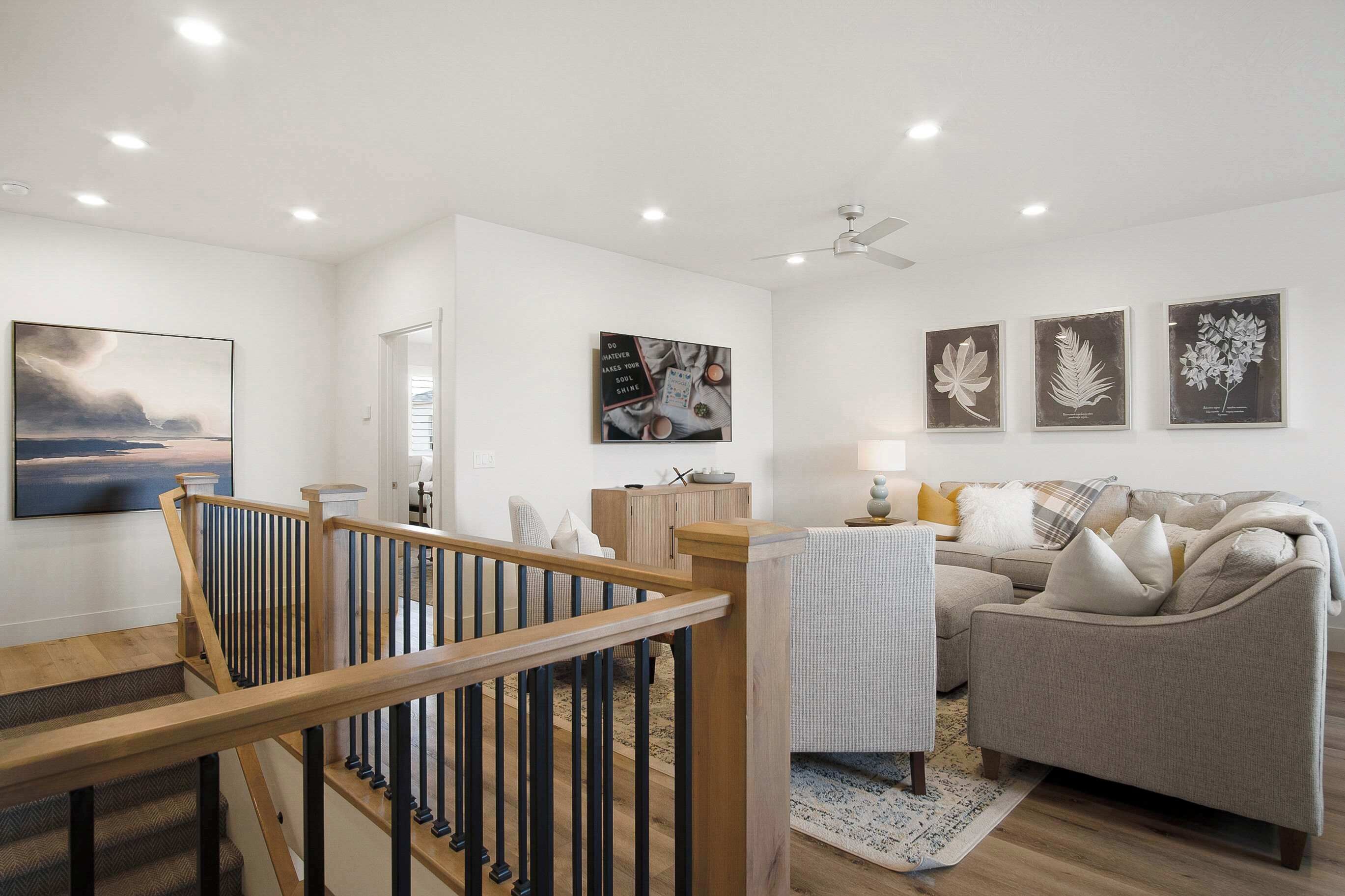 A modern living room with a staircase, a sofa, and artwork on the walls.