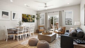 Un salon moderne comprenant un coin repas, un canapé, des poufs et une table basse.