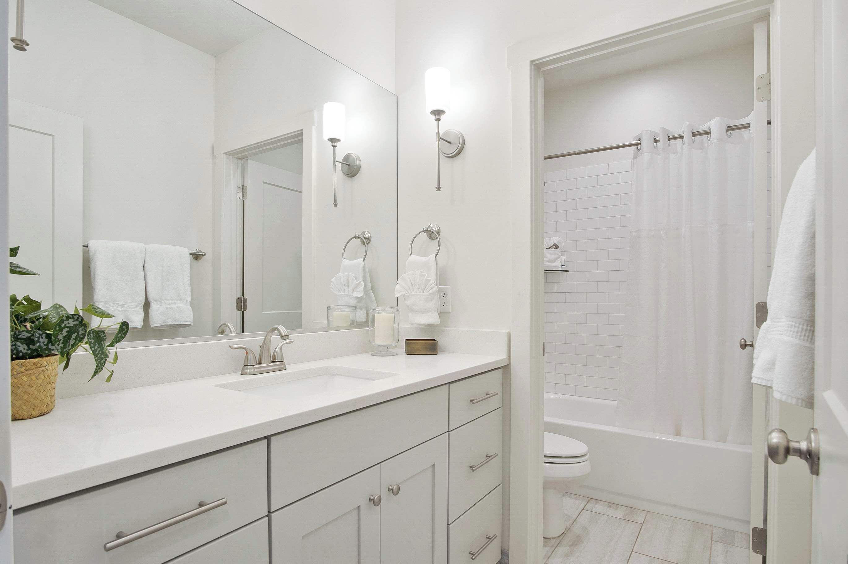A modern bathroom with a white sink, mirror, and shower curtain.