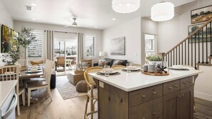 Une cuisine moderne dotée d’un îlot central, d’un coin repas avec des chaises et d’un escalier menant à un autre niveau.