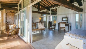 A spacious room with a large bed, a desk, and a chair. There is a window with curtains and a view of the outside. - La Torre by Interhome (Sovicille)