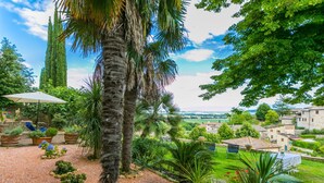 A garden with palm trees, potted plants, and a view of a village. - La Torre by Interhome (Sovicille)