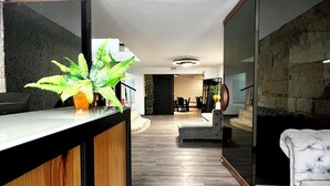 Un espace d’accueil moderne avec un comptoir en bois, une plante en pot et un mur en pierre.