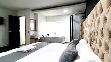 Une chambre d’hôtel moderne dotée d’un grand lit, d’une salle de bain avec baignoire et offrant une vue sur la ville.