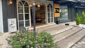 L’entrée d’un hôtel, avec une enseigne indiquant « Hôtel Orbe », se distingue par sa façade moderne, ornée de fenêtres en arc de cercle et d’un mur en pierre.